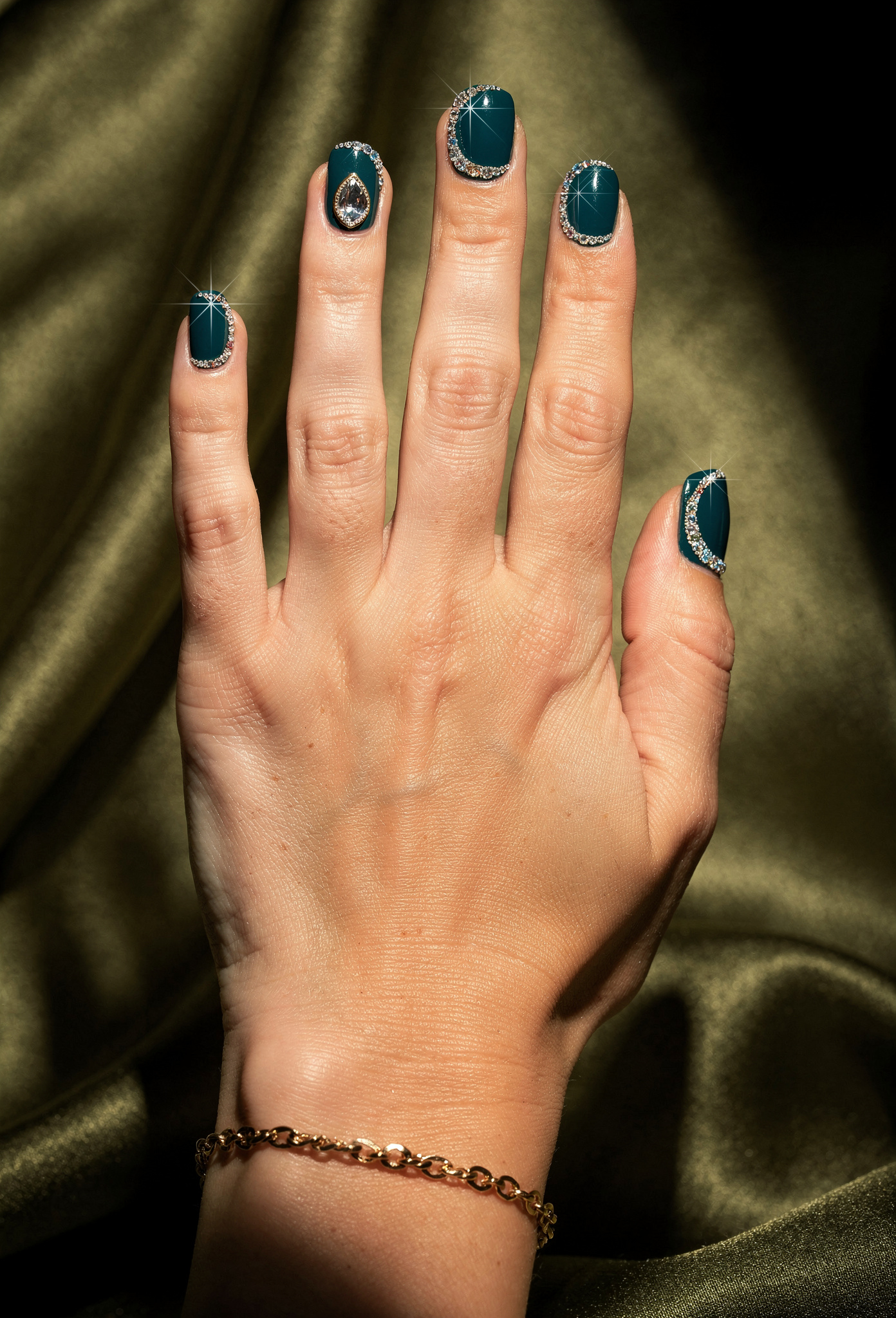 Kristal taşlarla süslenmiş koyu teal tırnak tasarımı